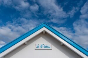 A minimalist view of a beach hut roof with blue and white colors set against a vibrant blue sky.