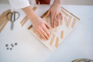 Hands arranging wooden pieces on a table for a DIY craft project indoors.
