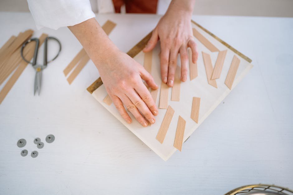 Hands arranging wooden pieces on a table for a DIY craft project indoors.
