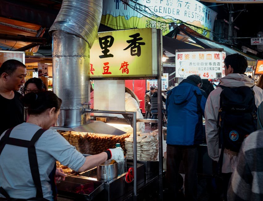 People enjoy street food at a vibrant Taipei night market.