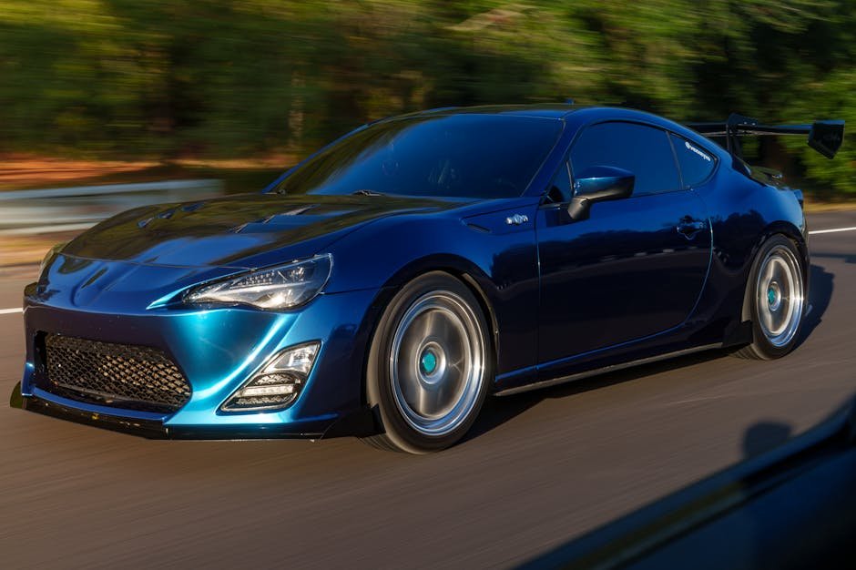 Blue sports car speeding down a highway, showcasing motion and design.