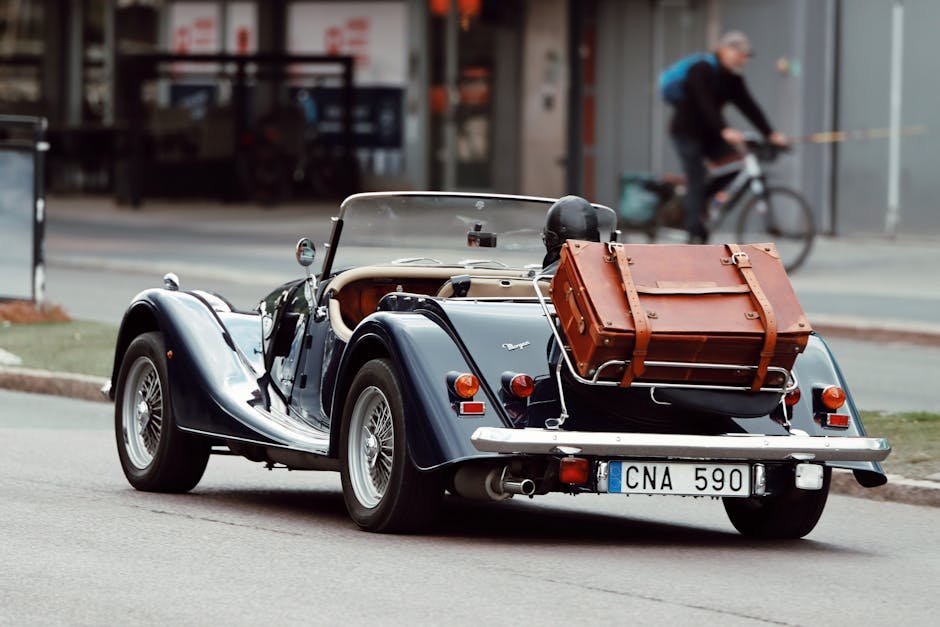 Vintage convertible car with a suitcase driving on a city street in Jönköping, Sweden.