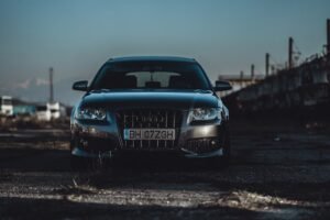 A stylish vehicle parked in a gritty industrial district during the day.