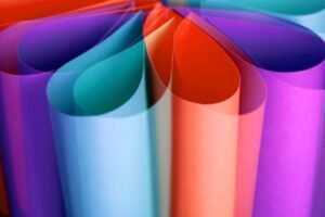 Vibrant abstract composition of rolled colorful paper sheets in close-up view.